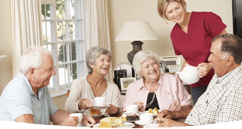 A group of elderly people having a cream tea with a support worker